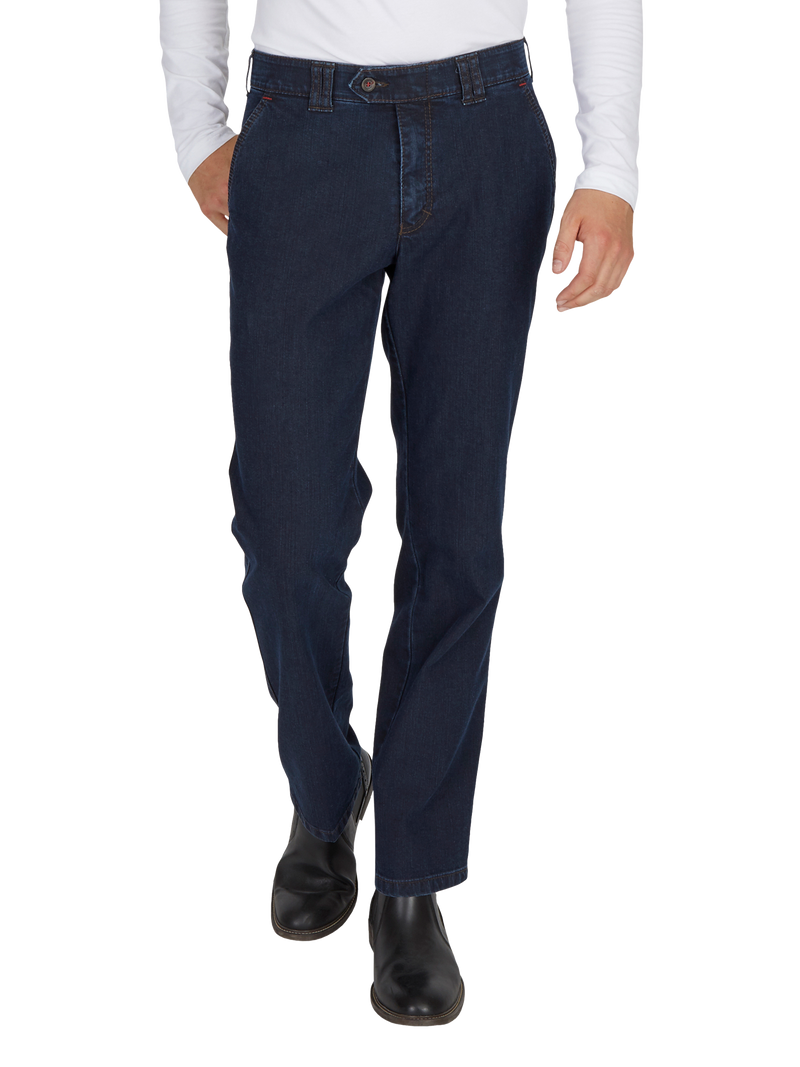 Hose in dunklem Blau, gerade geschnitten, mit Gürtelschlaufen, eine horizontale Tasche auf der linken Seite, getragen von einer Person mit weißem Oberteil und schwarzen Schuhen, stehende Haltung.