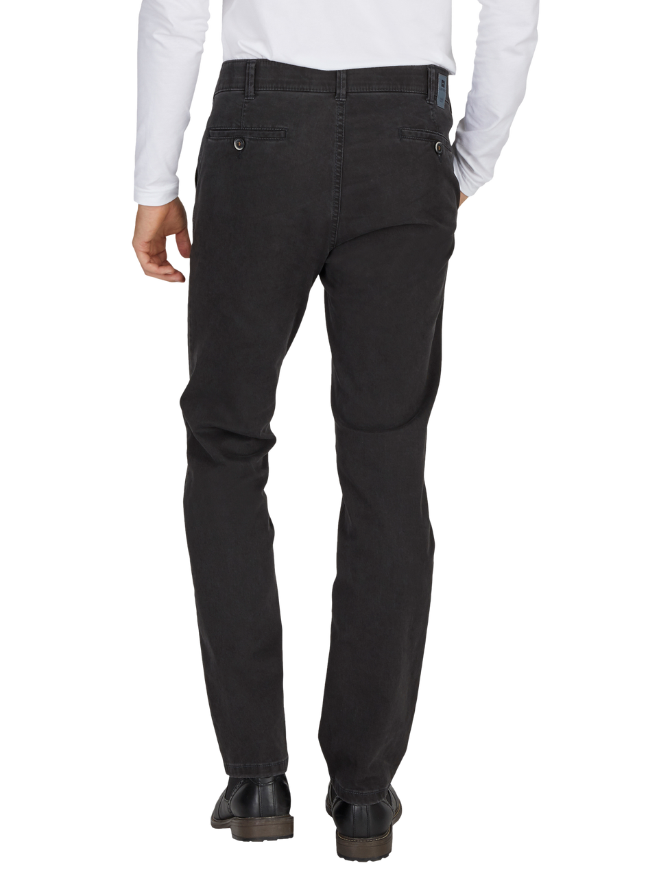 Ein Mann trägt schwarze Jeans, eine weiße Hemd und schwarze Schuhe. Der Fokus liegt auf den schwarzen, lässigen Hosen, die hinten mit zwei Knopf-Geldbörsen-Taschen versehen sind.