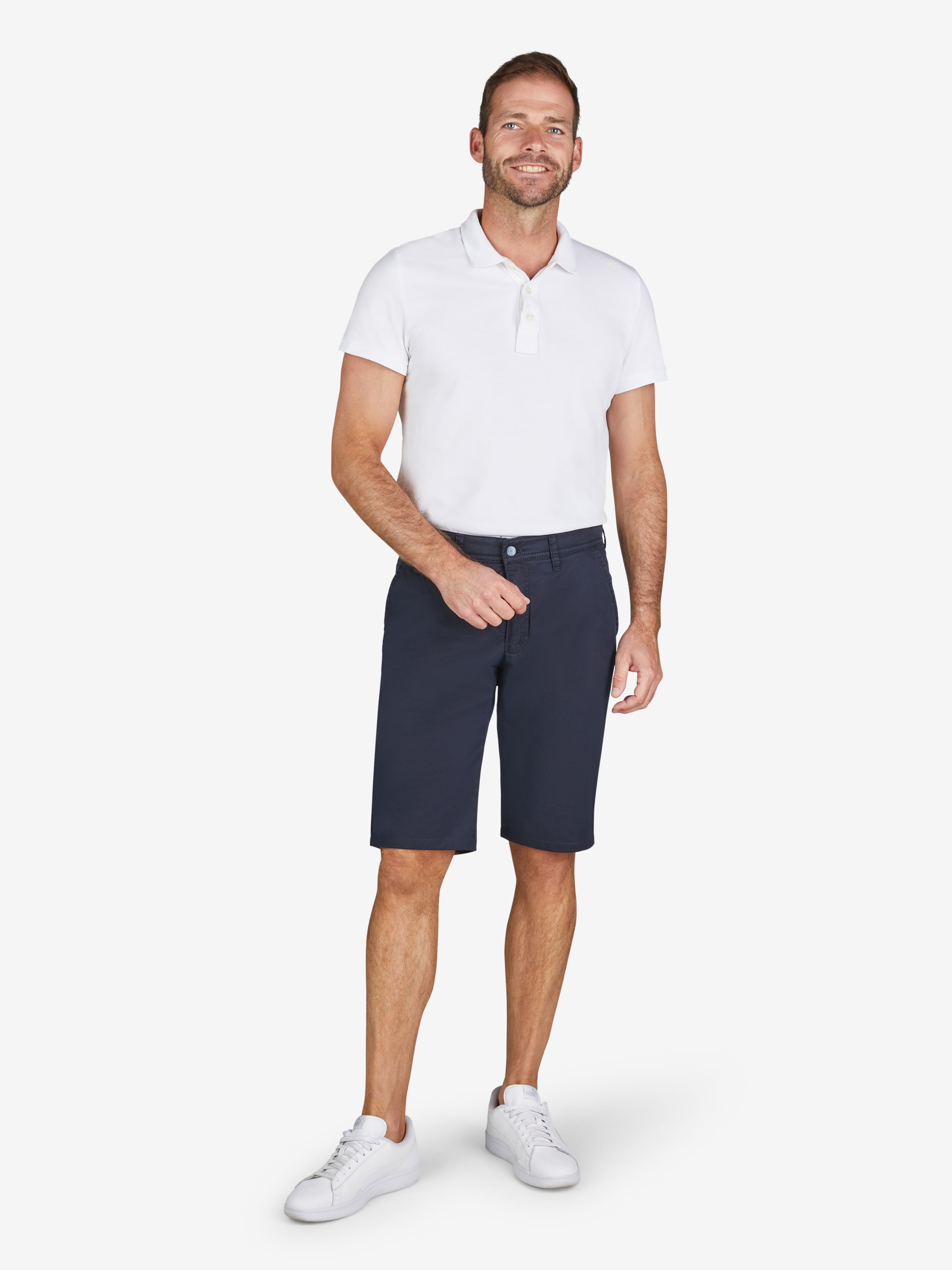 Mann trägt weiße Polo-Hemd und blaue Bermuda-Shorts aus Baumwoll-Tencel®-Mix mit elastischem Comfortbund, Hemdenstopper und High-Stretch-Qualität, hergestellt von Club of Comfort, Produkt ESPANA 8109 in marineblau, gerade Passform, Frühjahr/Sommer, frontal.