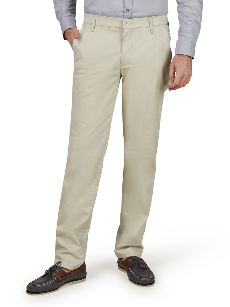 Herrenhose in cremefarbenem Stoff, gerade Passform, mit Gürtelschlaufen, seitlichen Eingrifftaschen und hinteren Paspeltaschen. Herren trägt dazu braune Lederschuhe und ein hellgraues Hemd.