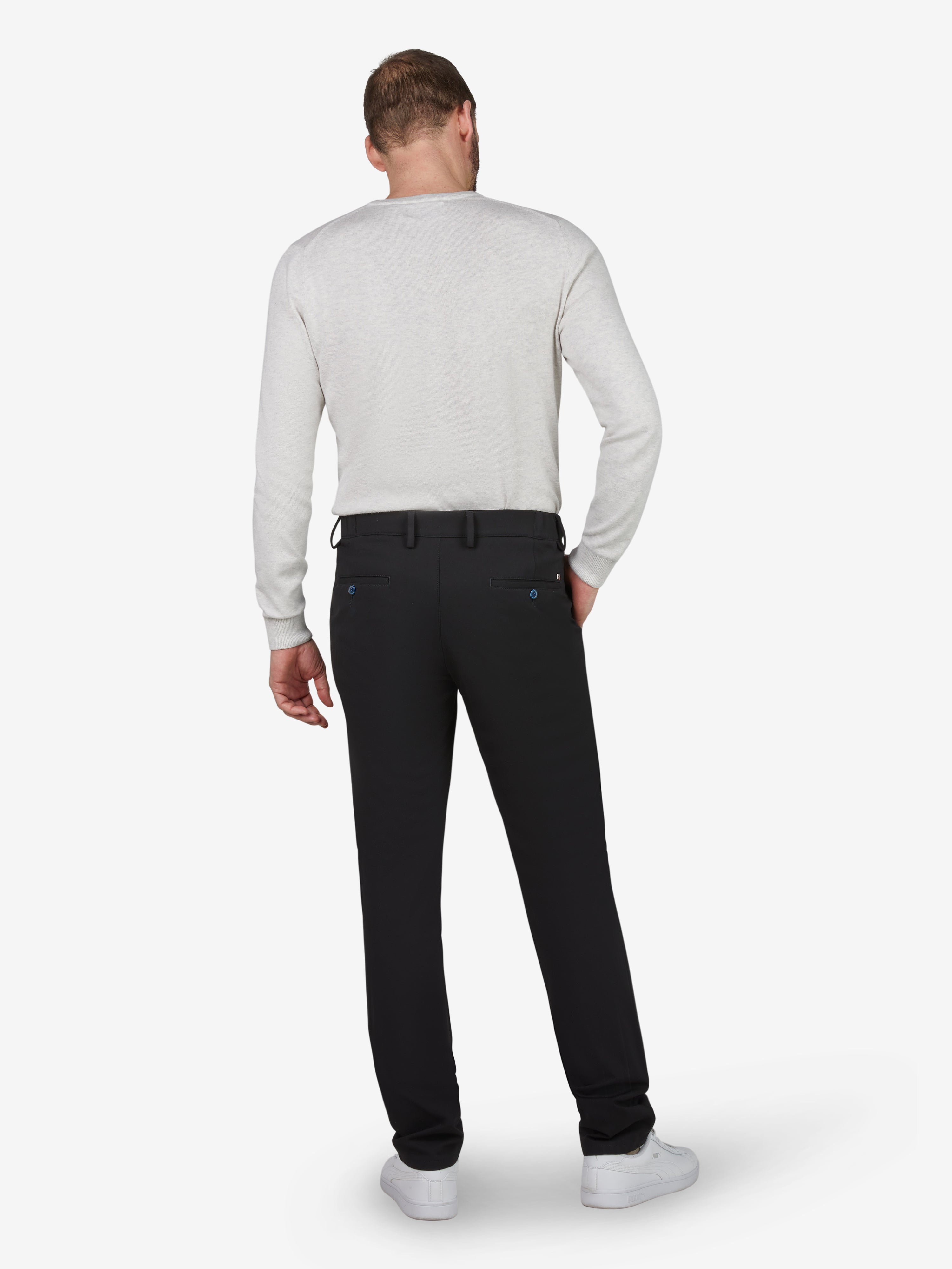 Herrenmodel trägt schwarze FOXX 8240 Chino-Hose in Slim Fit mit mittlerer Leibhöhe, elastischem Smokbund und Hemdstopper, gefertigt aus hochelastischem Polyamid-Viskose-Mix mit Microstruktur, bequem auch in Ganzjahresnutzung, seitlich eingepasst mit Mobiltelefon-Tasche, EU-Größe, auf weißem Hintergrund.