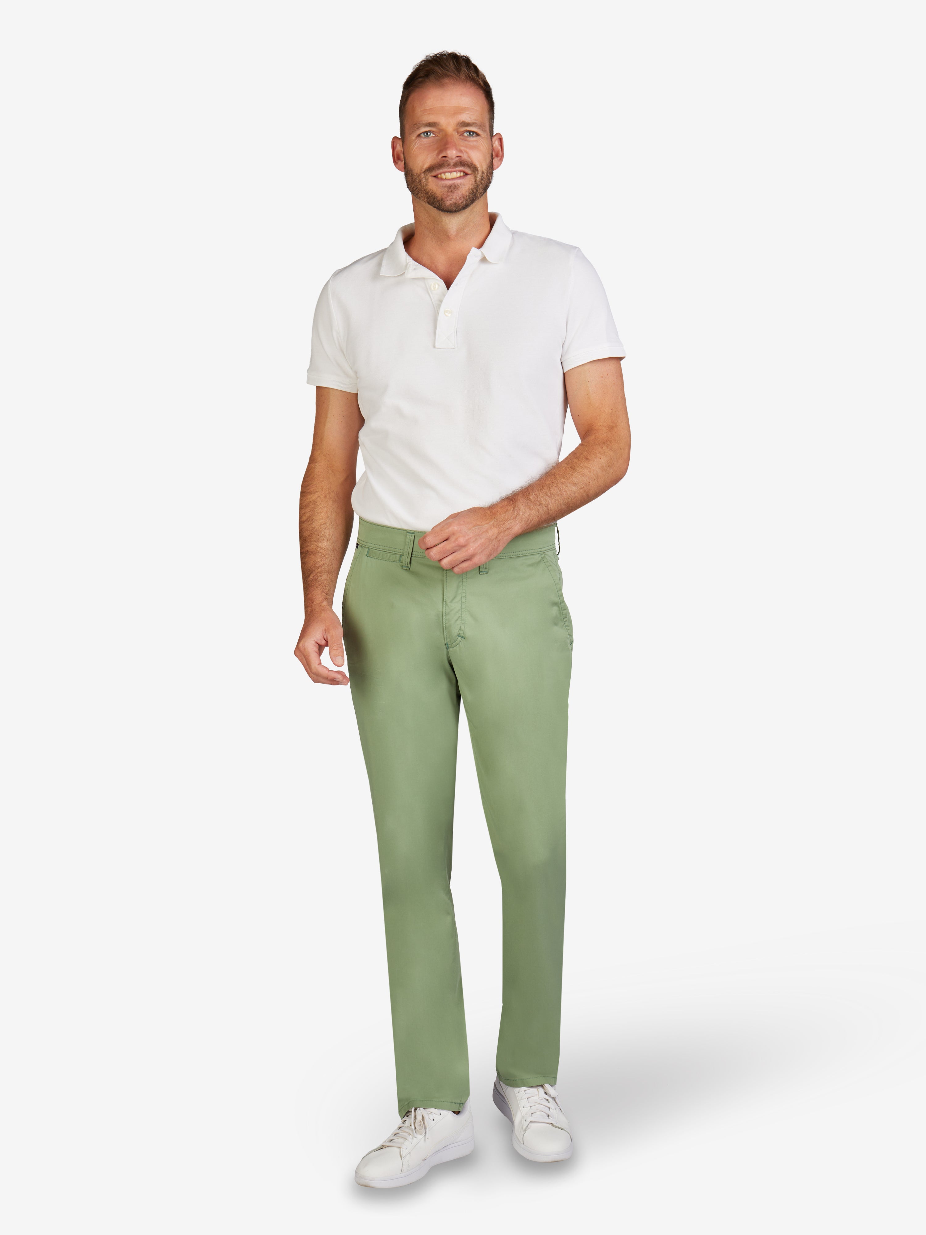 Mann trägt hellgrüne GARVEY Flat Front-Hose aus nachhaltiger Baumwolle mit COLDBLACK-Ausrüstung, elastischem Komfortbund, geradem Fit, schmaler Fußweite, leichter Baumwollqualität (260 g/lfm), passend für Frühjahr/Sommer, kombiniert mit weißem Polo-Shirt, auf weißem Hintergrund.