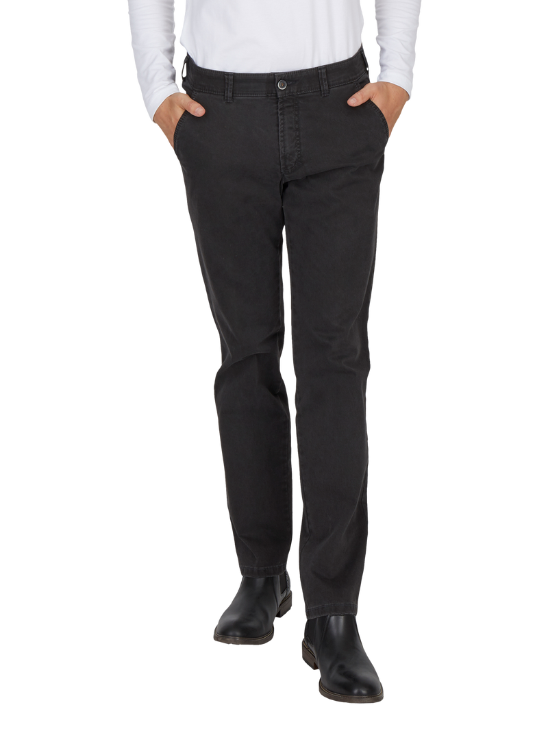 Ein Mensch trägt schwarze Jeans, die in der Taille sitzen, mit den Händen in den Taschen. Die Jeans sind gerade geschnitten und mit schwarzen Schuhen kombiniert.