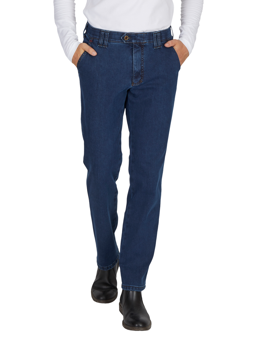 Nahaufnahme eines Menschen mit dunklen Jeans, die an der Taille sitzen und in den Taschen ruhen, sowie schwarzen Stiefeln. Die Person trägt eine weiße, langärmlige Bluse. Die Bilderfassung zeigt den unteren Brustbereich bis zu den Füßen.