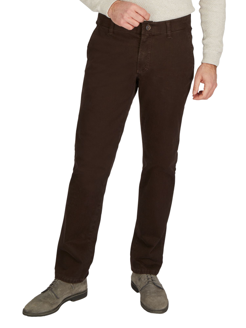 Hosenmodell in dunkler brauner Farbe, getragen von einer Person. Die Hose hat einen normalen Bund, Gürtelschlaufen, eine Reißverschlussöffnung mit Knopf und seitliche Eingrifftaschen. Die Person trägt grau-schwarze Schuhe und eine hellgraue, langärmlige Oberbekleidung.