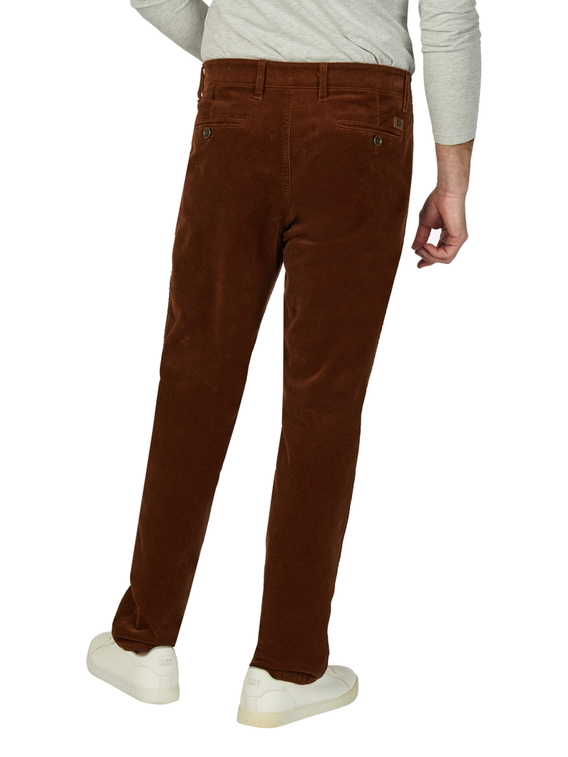 Blick auf eine Person, die braune Cordhosen trägt, sichtbar von hinten. Die Person trägt eine helle Graue Oberbekleidung und weiße Sneakers.