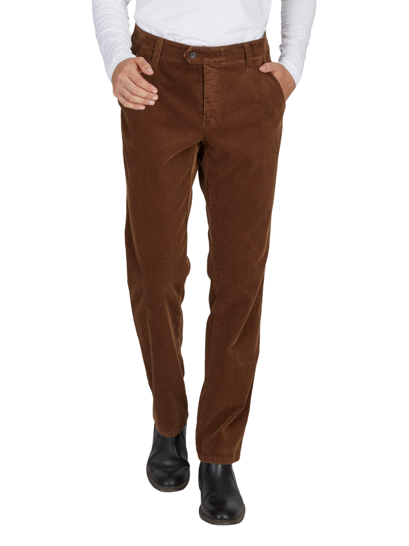 Hosenbein mit braunen Cordhosen, dunkle Schuhe, sichtbar von Hüfte bis Fuß, Person trägt eine weiße Bluse.