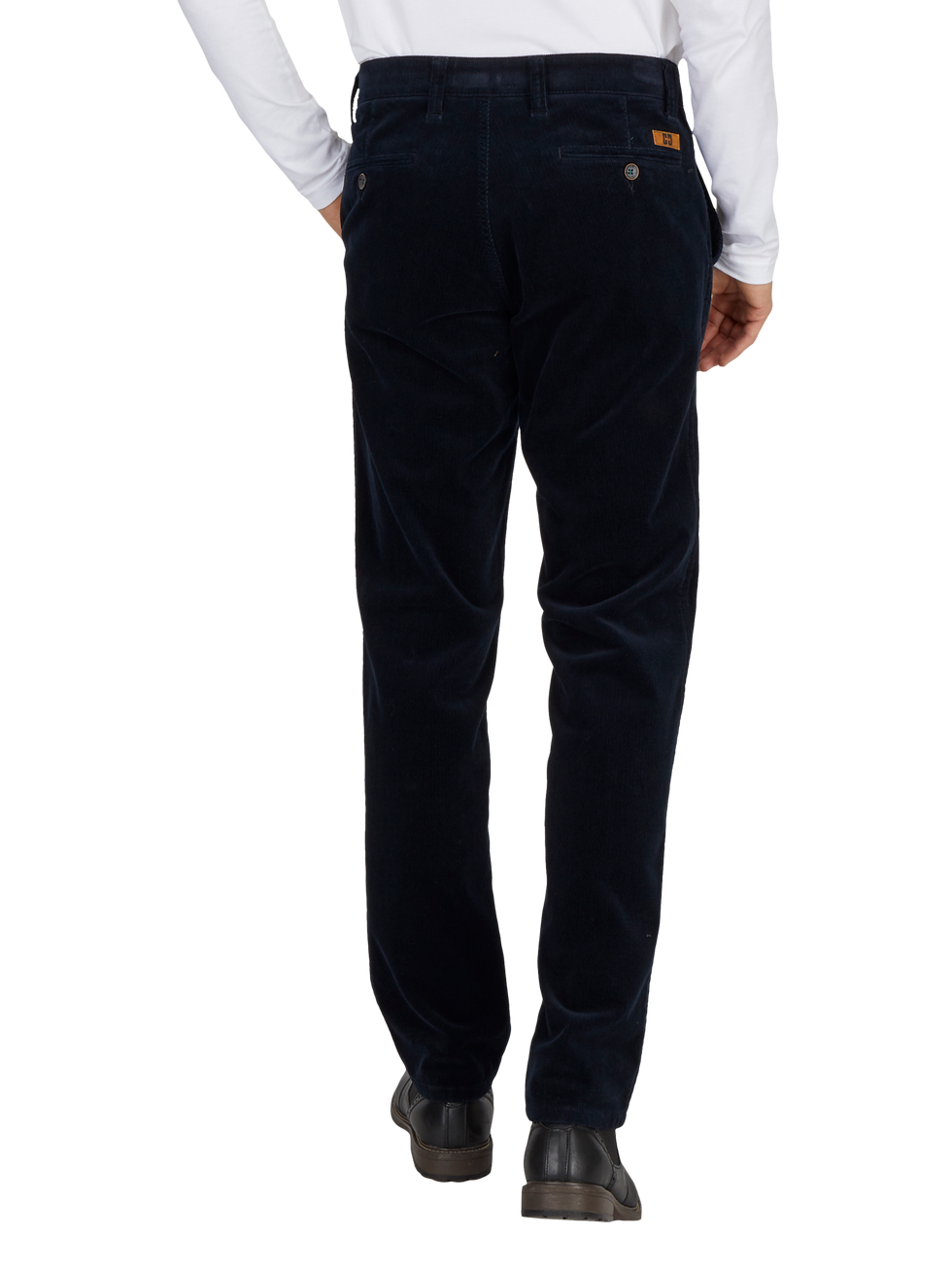 Herrenhose aus dunklem, weichem Cordstoff, getragen von einer Person, die eine weiße Hemd trägt. Die Hose hat eine normale Passform, seitliche Eingrifftaschen, hintere Taschen mit Knöpfen und eine kleine Leder-Logoplatte am Gürtel.