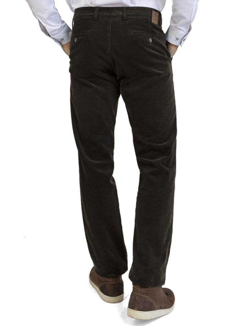 Der Bildausschnitt zeigt eine Person, die schwarze Jeans trägt, wobei der Rücken sichtbar ist. Die Person trägt eine weiße Hemd, die in die jeans gesteckt ist, und braune Schuhe. Die Haltung ist entspannt, mit den Händen in den Taschen.