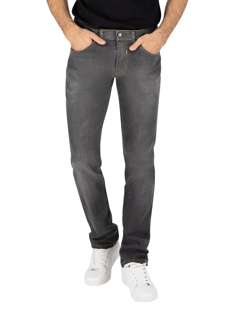 Ein Mann trägt eine dunkle Jeanshose, die vorne mit den Händen in den Taschen liegt. Die Jeans ist leicht ausgewaschen, hat eine normale Passform und ist mit weißen Sneakern kombiniert.