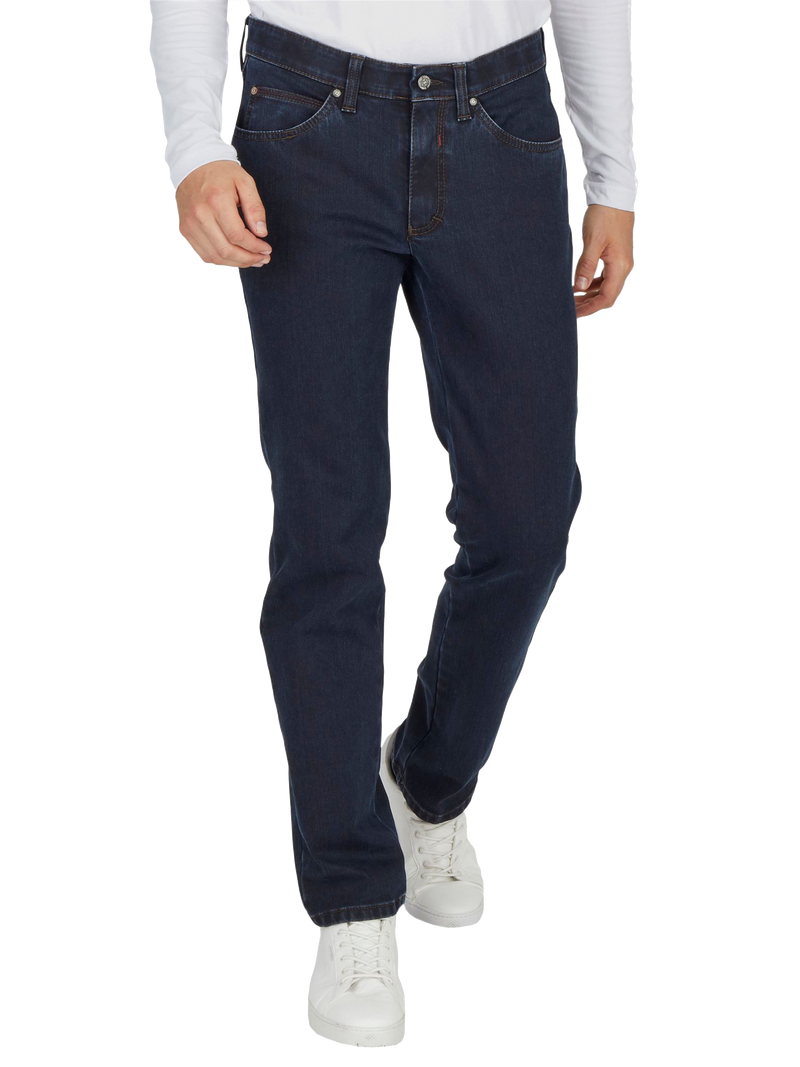 Bilderbeschreibung: Person trägt eine weiße Langarmbluse, dunkle Jeanshose und weiße Sneakers. Die Person steht aufrecht, eine Hand in die Tasche.