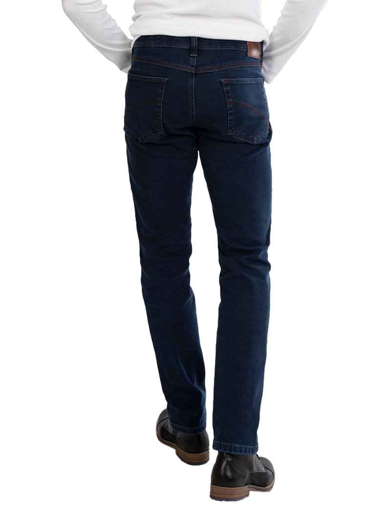 Blick auf die Rückseite eines Mannes, der dunkle Jeans trägt, die eng sitzen und an den Hüften sowie den Beinen gut passen. Er trägt einen weißen Pullover und schwarze Schuhe.