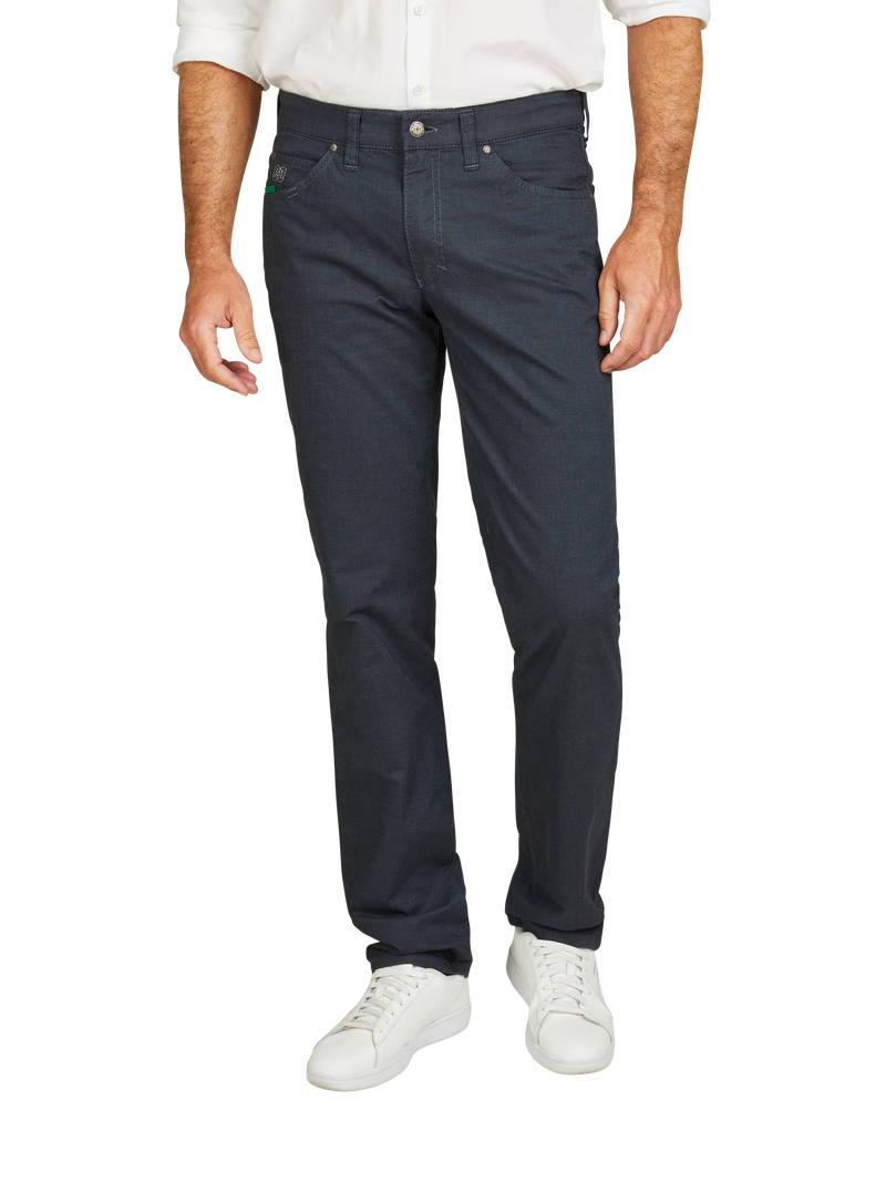 Hosenmodell: Dunkelblaue, gerade geschnittene Jeanshose mit sechs Gürtelschlaufen, fünf Gürtelschlaufen sichtbar, Reißverschluss und Knopf vorne. Passend kombiniert mit weißen Turnschuhen, weißem Hemd und sichtbaren Unterhemd.