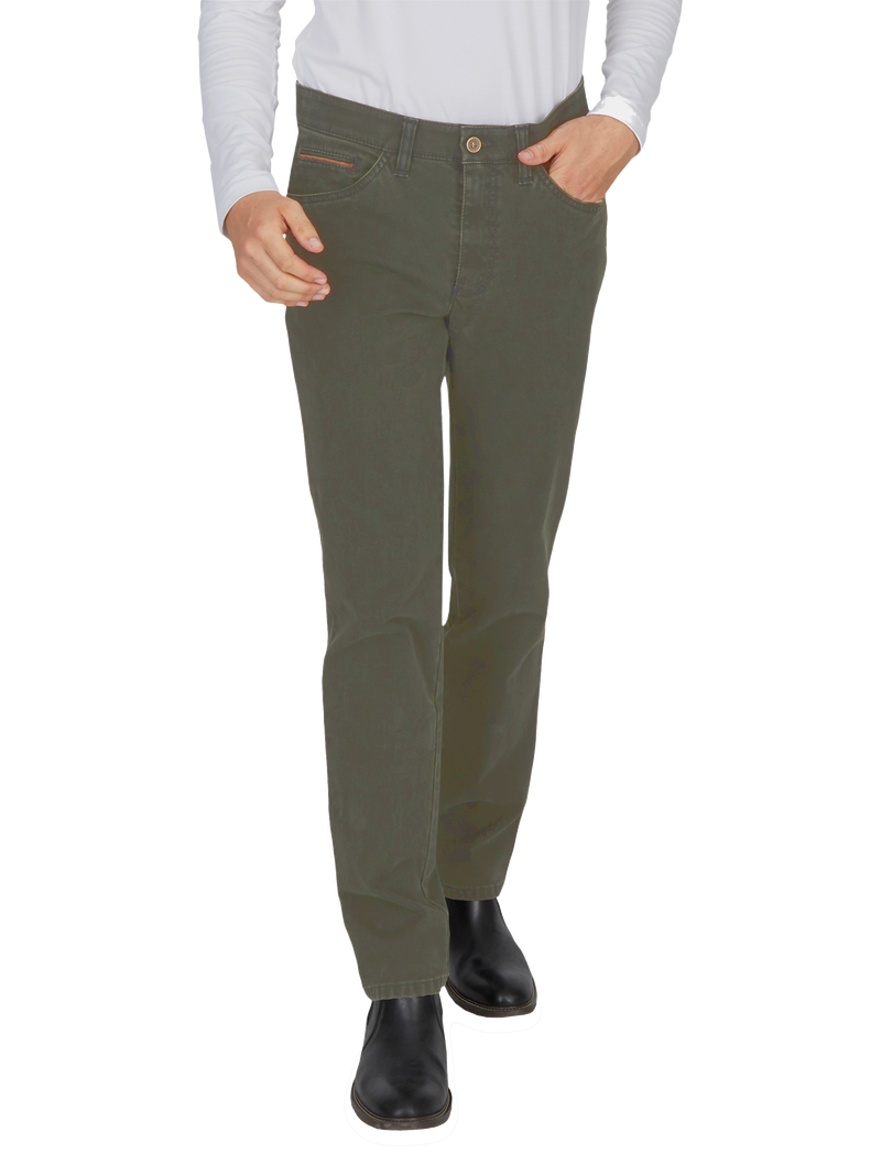 Blick auf eine Person, die grüne Jeans trägt, eine rechte Hand in der Hosentasche hat und schwarze Stiefel trägt. Die oberen Körperteile sind nicht sichtbar.