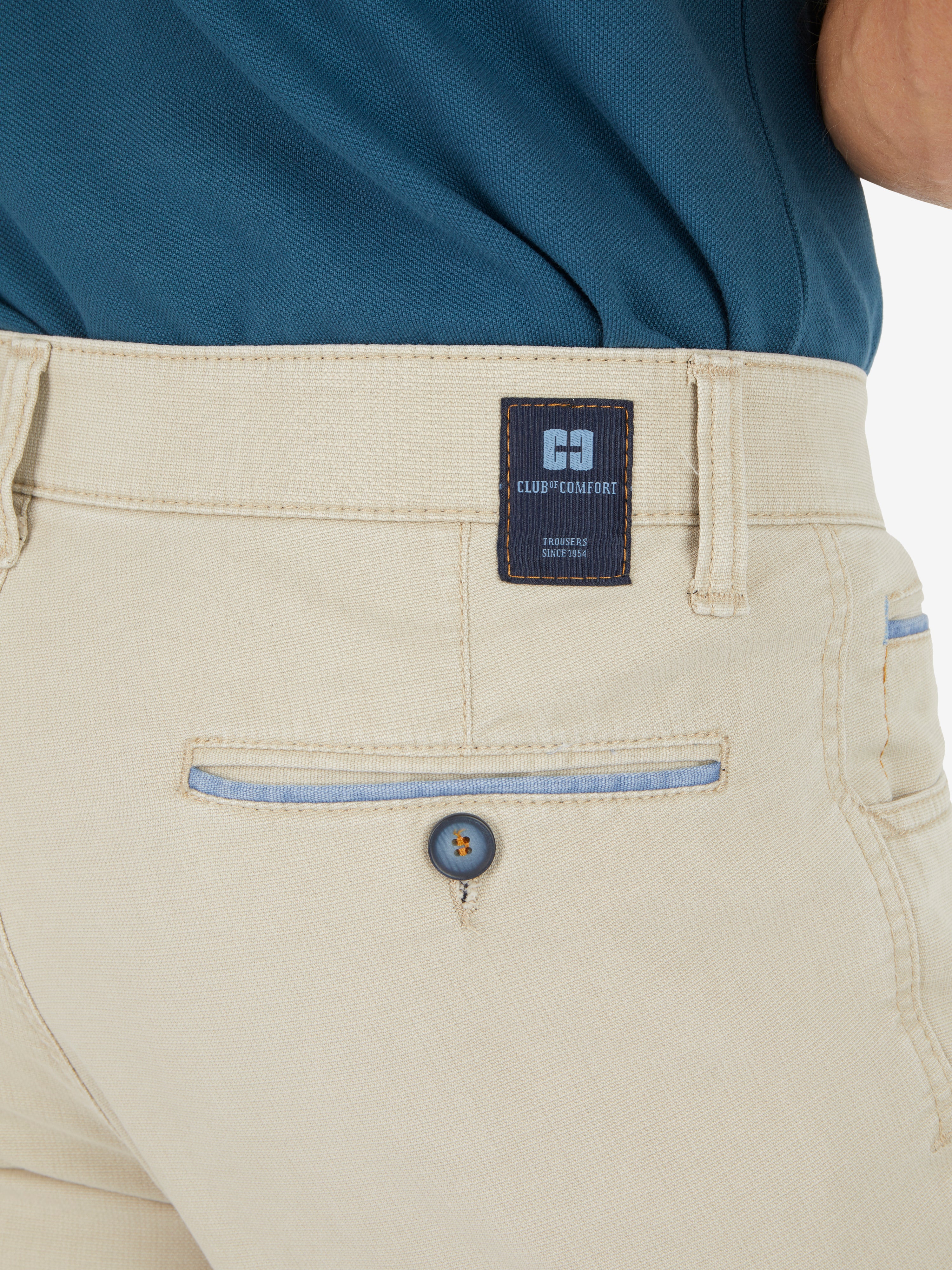 Nahaufnahme einer beige Hose "MARVIN 7506" von Club of Comfort, mit Komfortbund, Hemdenstopper, Swing-Pocket mit Kontrast-Patch, doppelt paspelierte Münztasche, hergestellt aus High Stretch-Baumwolle mit Mikrostruktur, normaler Leibhöhe und schlankem Bein, im Frühjahr/Sommer-Design.