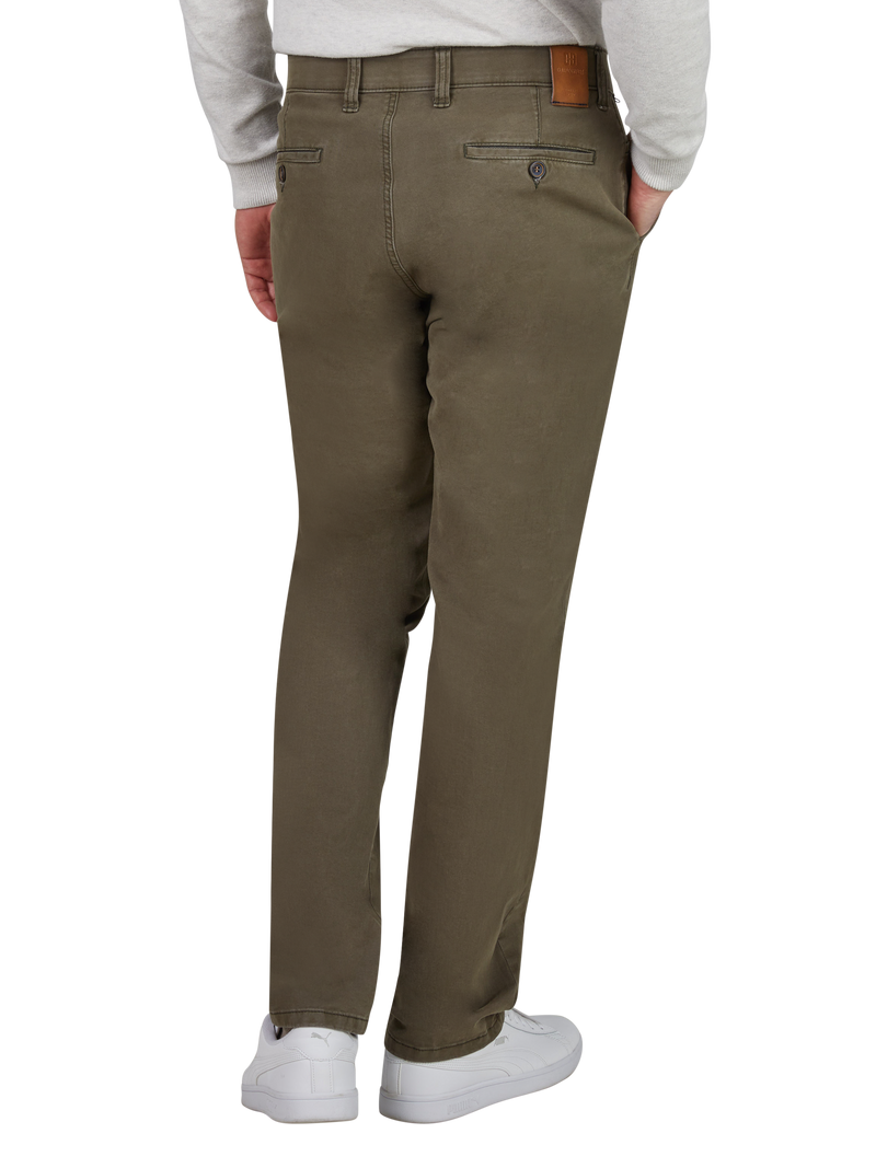 Blick auf die Rückseite eines Mannes, der khaki-farbige Chino-Hosen trägt. Die Hosen haben zwei Paspeltaschen mit Knopfverschlüssen auf der Rückseite. Der Mann trägt eine helle, langärmlige Oberbekleidung und weiße Sneakers.