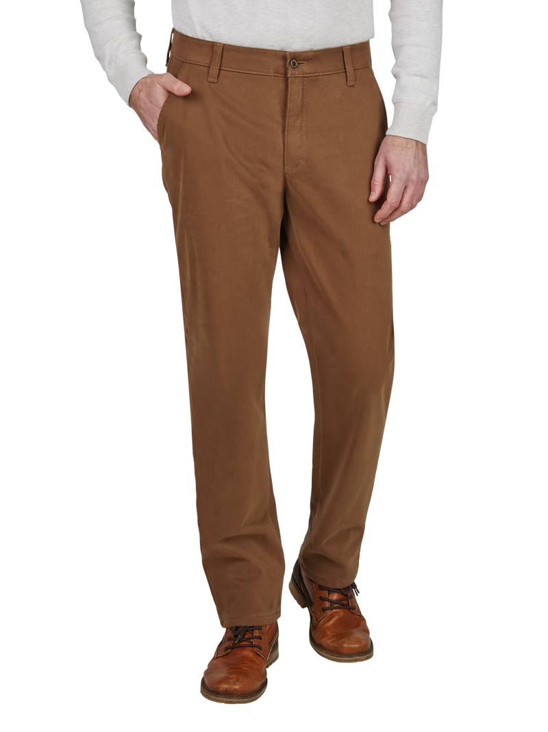 Ein Mann trägt braune, gerade geschnittene Baumwollhose mit Gürtel und Taschen, kombiniert mit einem hellgrauen Pullover und braunen Lederschuhen.