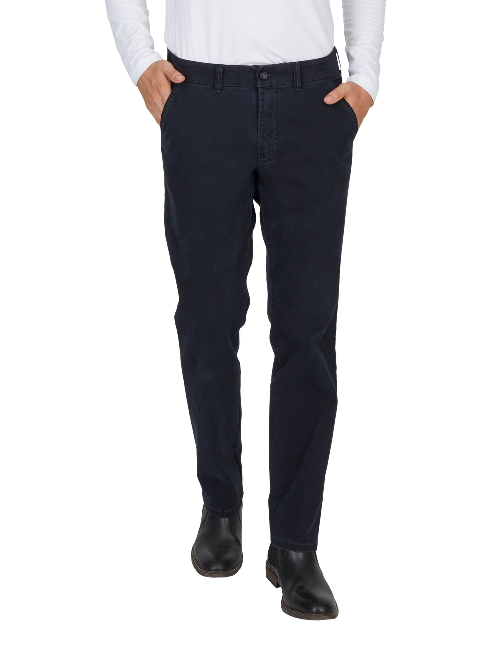 Hosenansicht einer Person, die dunkelblaue, lässige Jeans trägt. Die Person hat die Hände in den Taschen, trägt schwarze Schuhe und ein weißes, langärmeliges Oberteil.