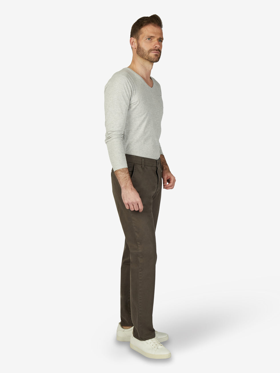 Mann trägt eine steingraue GARVEY 7612 Flat Front-Hose aus Hochstretch-Baumwolle mit Komfortbund, Hemdenstopper und Münztasche, kombiniert mit einem hellgrauen Pullover und weißen Sneakers, präsentiert vor neutralem Hintergrund.