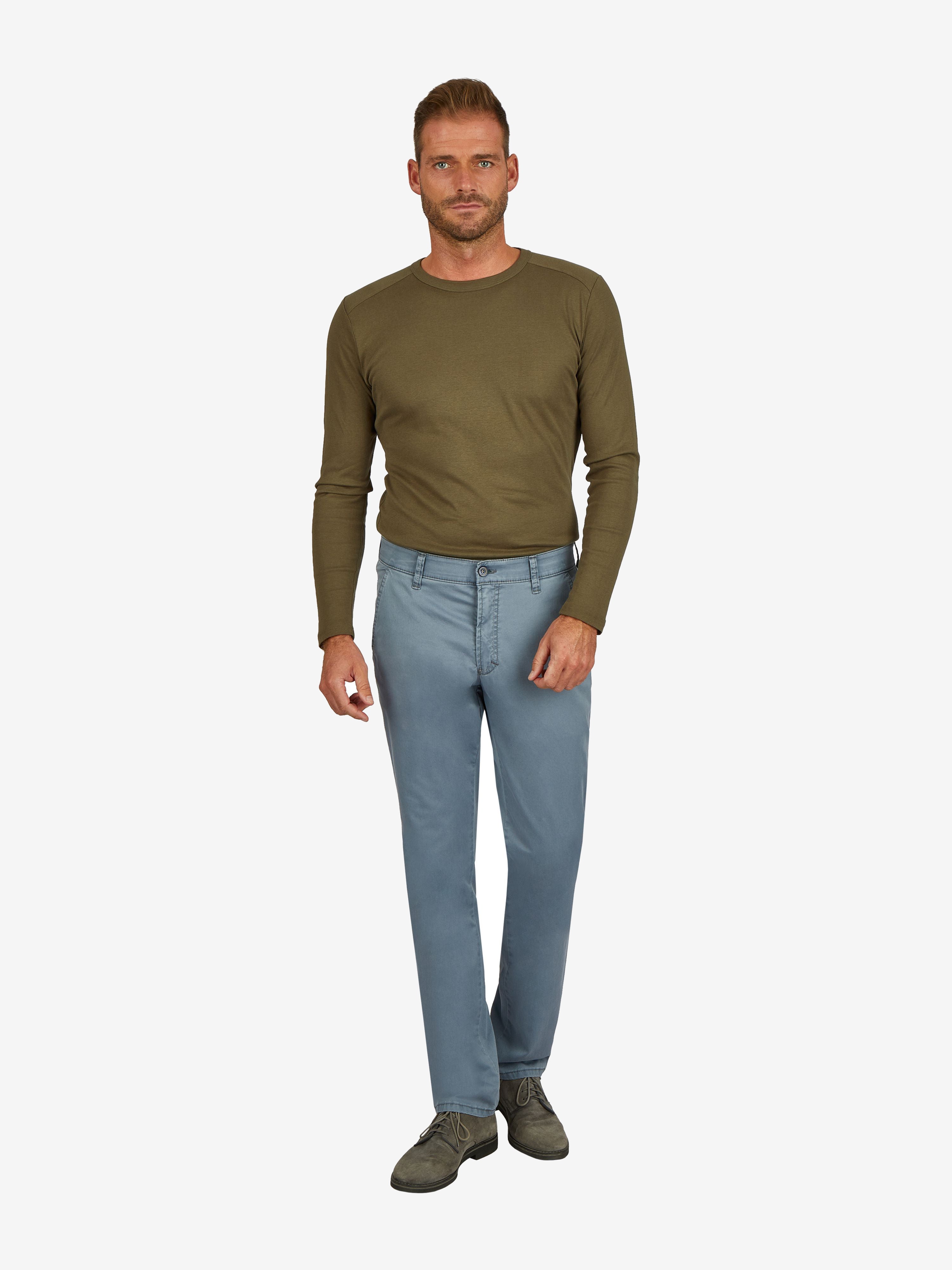 Mann trägt eine rauchblau GARVEY Flat Front-Hose aus Baumwoll-High Stretch mit elastischem Komfortbund, Hemdenstopper und normaler Leibhöhe, kombiniert mit einem grünen Longsleeve.