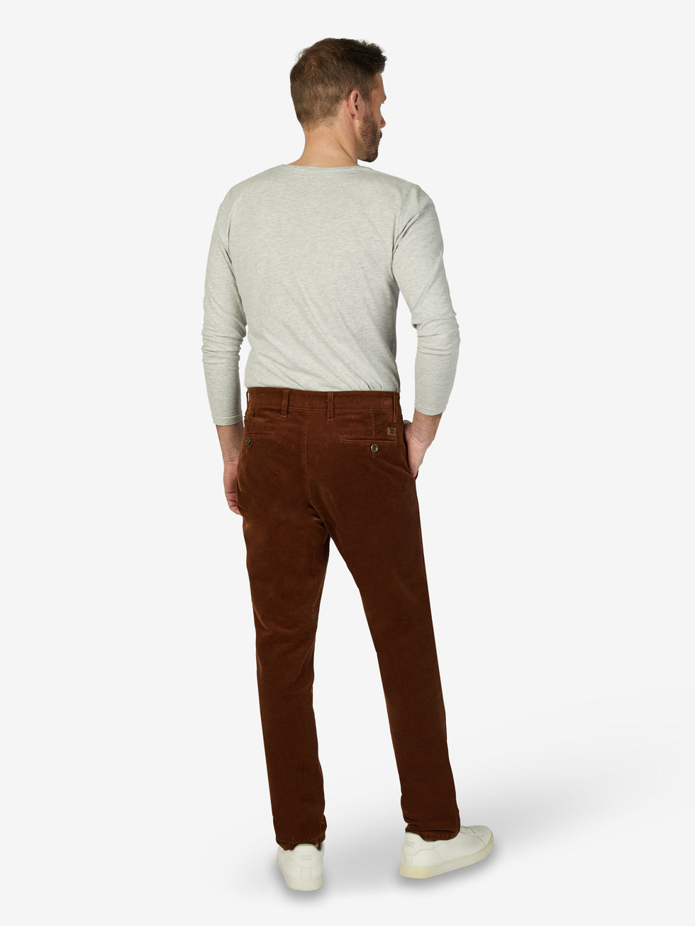 Mann trägt braune GARVEY 8200 Flat Front-Hose aus Feincord mit Stretch, elastischem Komfortbund, Hemdenstopper, normaler Leibhöhe, schmaler Fußweite, modisch casualer Optik, auf weißem Hintergrund, seitlich sichtbar.