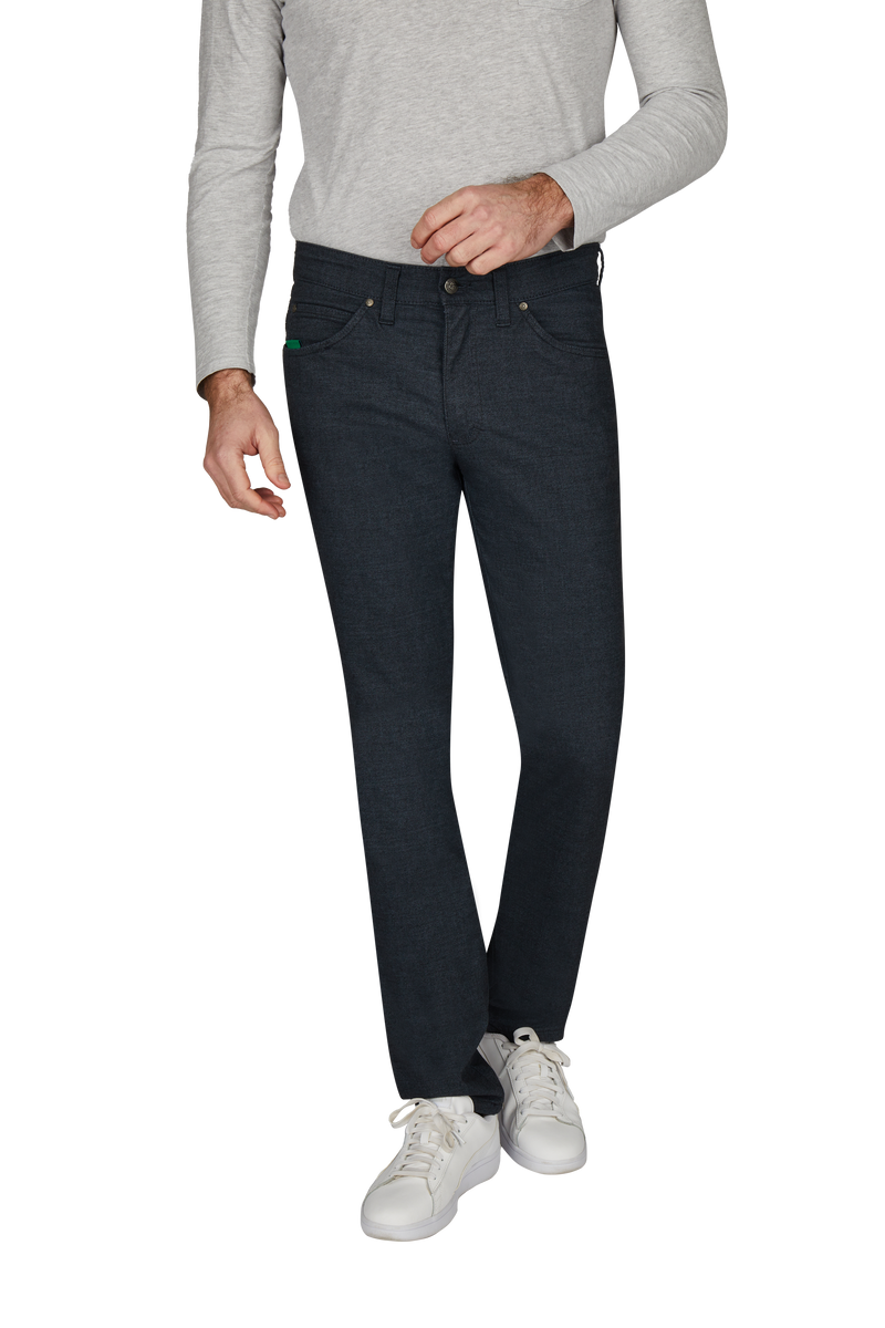 Ein Mann trägt dunkelblaue Jeans, ein hellgraues langärmeliges Oberteil und weiße Sneakers.