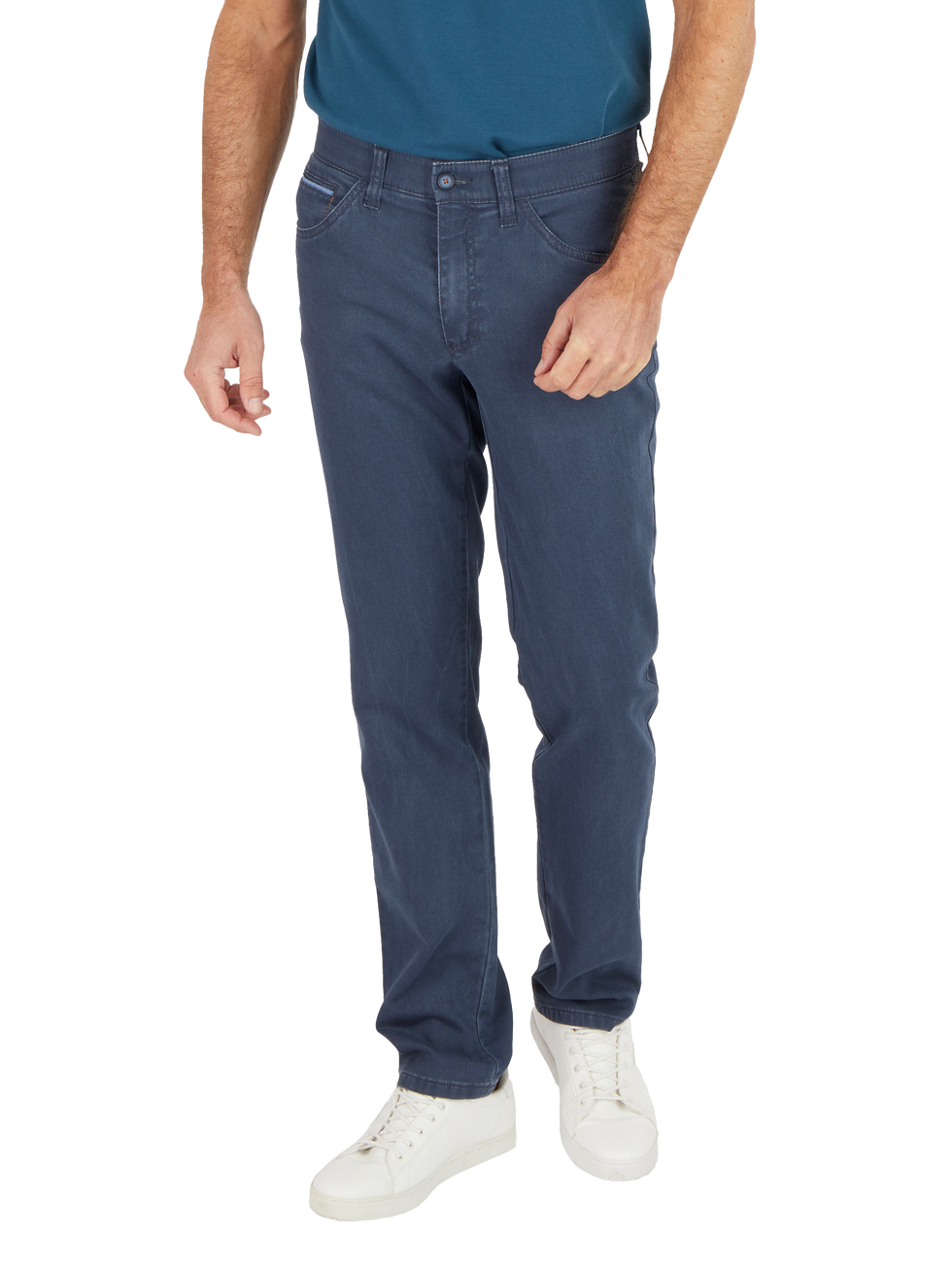 Ein Mann trägt dunkle Jeans, ein blaues T-Shirt und weiße Sportschuhe. Der Fokus liegt auf den sitzenden, lockeren Jeans, die casual und bequem aussehen.