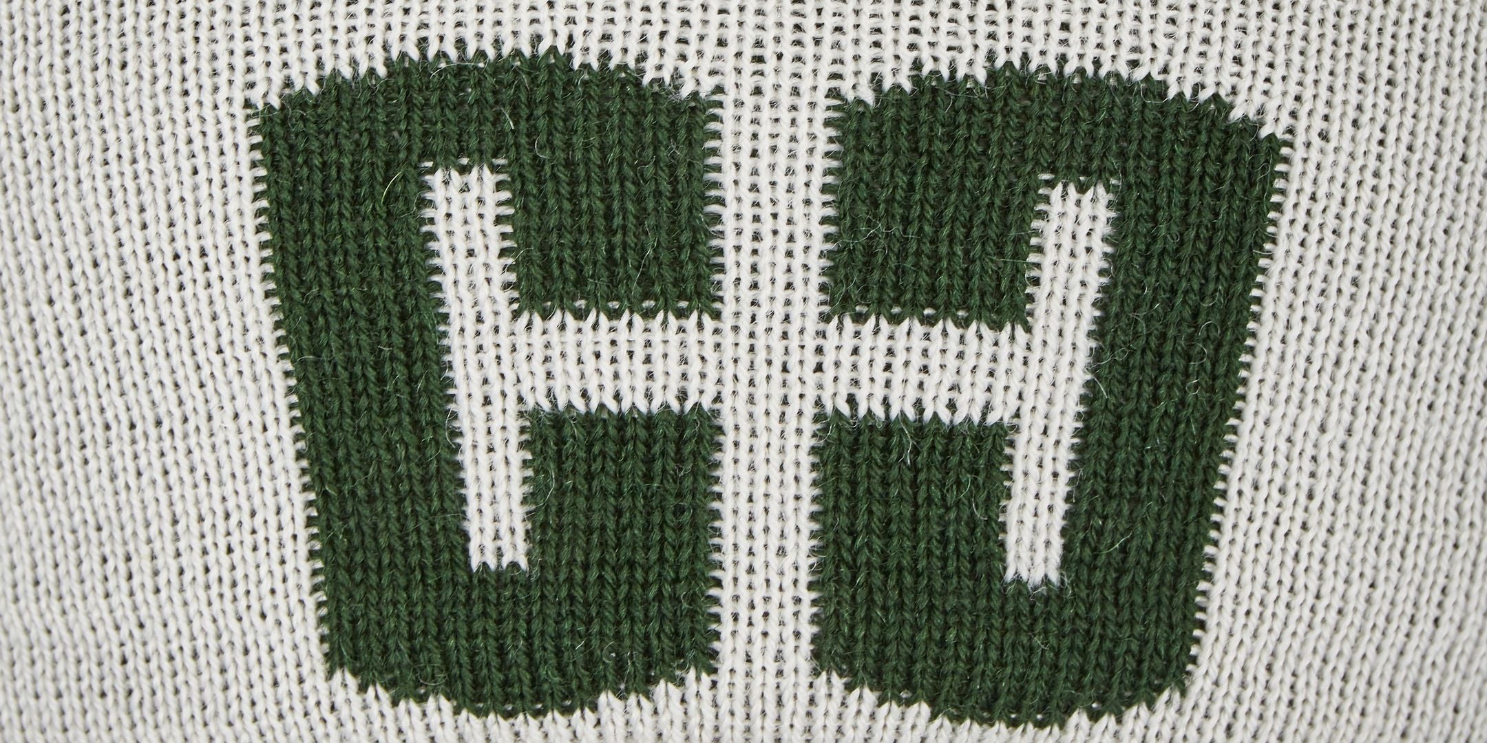 Ein Stoffbild mit stickierten, großen grünen Buchstaben "C" und "J" vor einem weißen Hintergrund.